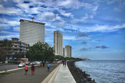 people walking on side walk beside beach