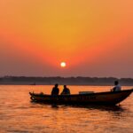 silhouette of 2 people riding on boat during sunset