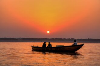 silhouette of 2 people riding on boat during sunset